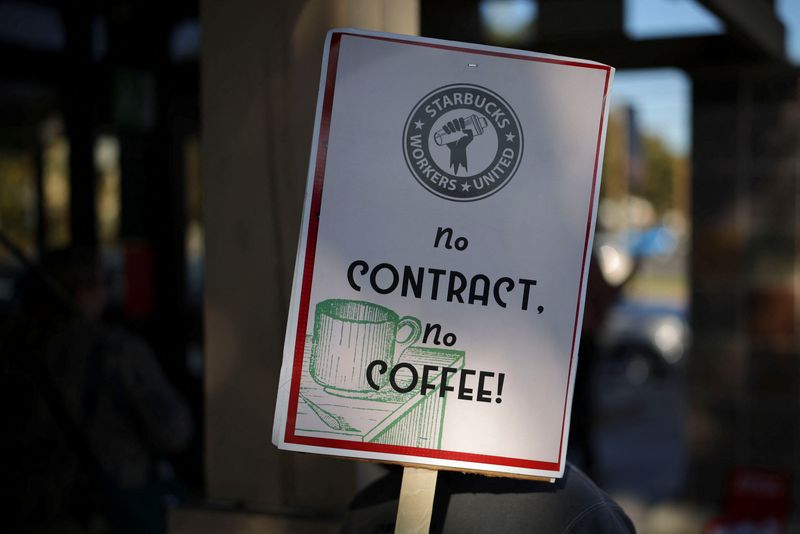 © Reuters. A person holds a sign as baristas picket in front of a Starbucks in Burbank, California, U.S., December 20, 2024. REUTERS/Daniel Cole