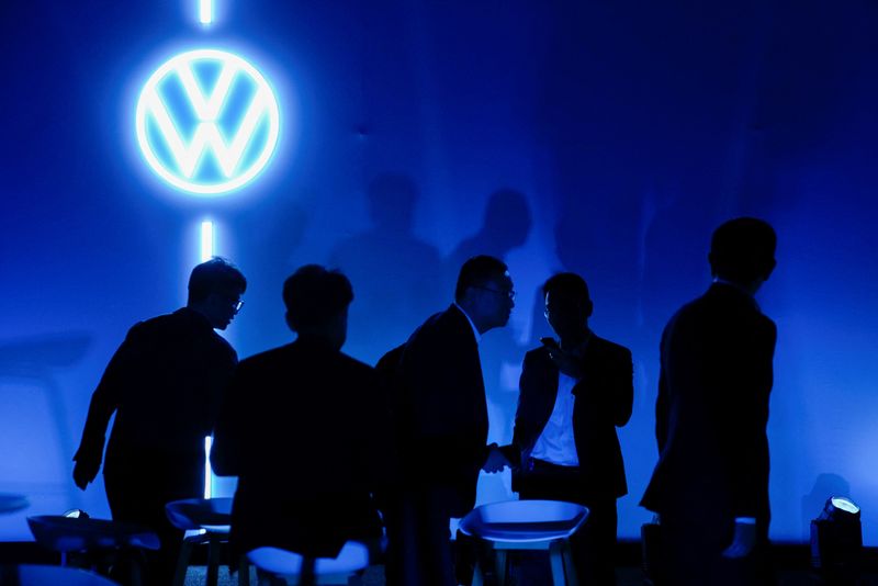 © Reuters. FILE PHOTO: People stand near the logo of Volkswagen as Volkswagen electric sedan ID.7 (not pictured) is debuted at an event ahead of the Shanghai Auto Show, in Shanghai, China April 17, 2023. REUTERS/Aly Song/ File Photo