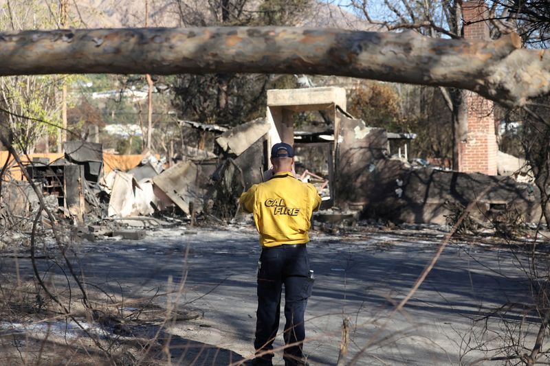 © Reuters. FILE PHOTO: A CalFire personnel takes photos of a structure burned during the Eaton fire in Pasadena, California, U.S., January 15, 2025. REUTERS/Mario Anzuoni/File Photo