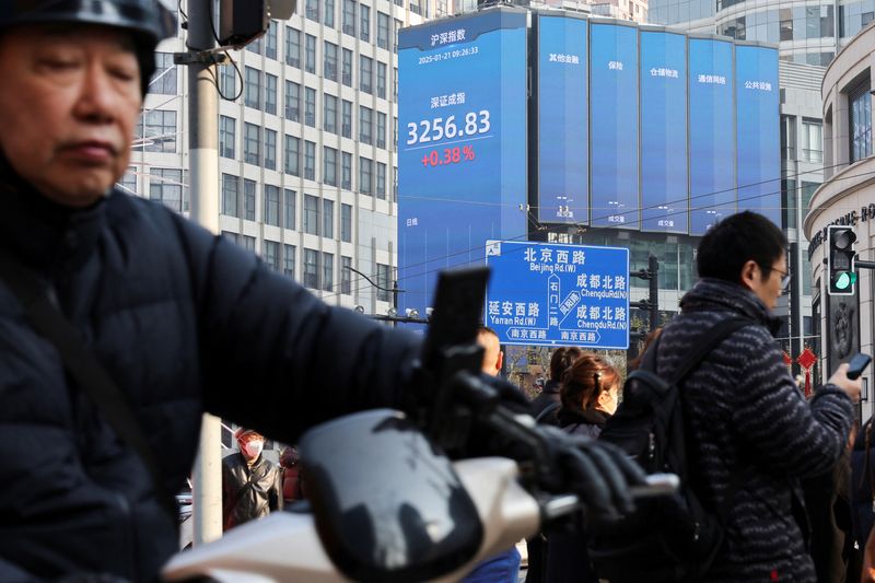 © Reuters. Pedestrians wait for a street signal on a sidewalk as an electronic billboard shows the Shenzhen stock index in Shanghai, China January 21, 2025.  REUTERS/Go Nakamura